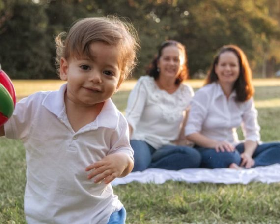A joyful family enjoying a picnic in the park with a playful toddler in the foreground.